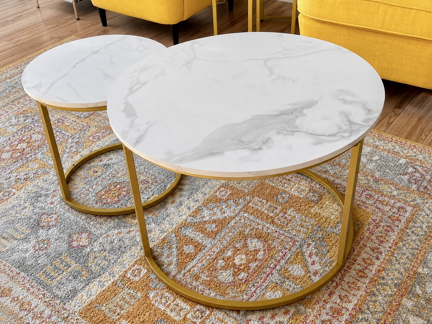 Marble-look nesting coffee tables with gold frames on a colourful patterned rug